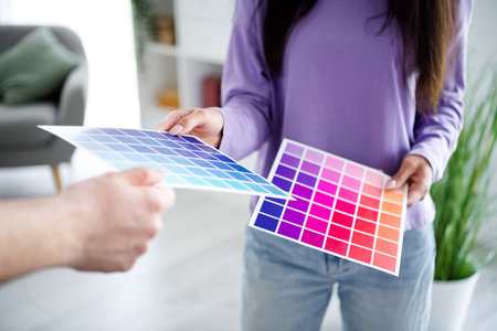 Young woman choosing vibrant color palette sheets indoors during daylight in modern living roomの写真素材