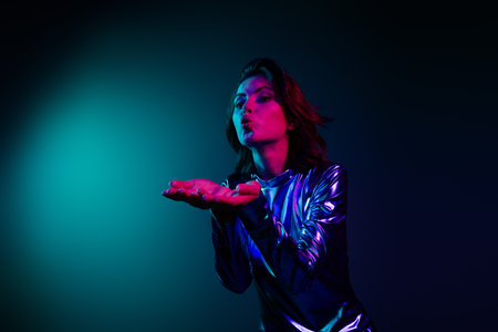 Portrait of stunning young woman send air kiss empty space wear shiny dress neon light dark blue...