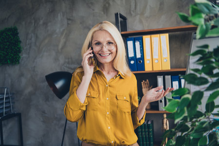 Photo of positive good mood lady specialist dressed shirt communcoating modern device indoors workstation workshopの写真素材