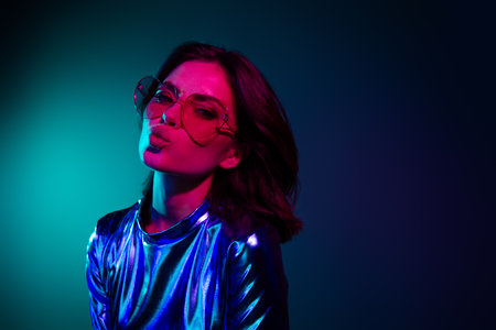 Portrait of stunning young woman kiss lips empty space wear shiny dress neon light dark blue backgroundの写真素材