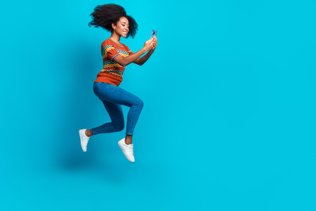 Full body length photo of young girl using smartphone isolated on blue color backgroundの写真素材