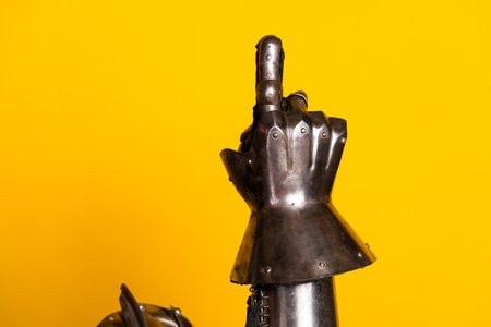 A knights armored hand gesturing on a vibrant yellow background conveying medieval braveryの写真素材