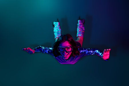 Full size photo of gorgeous young girl flying wear shiny dress glowing boots neon light dark blue...