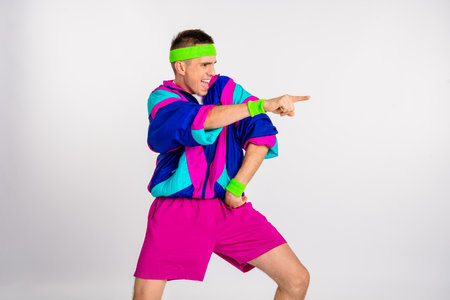 Energetic young man in retro workout attire strikes a dynamic pose, showcasing vibrant colors and a...