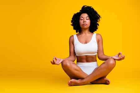 No filter studio photo of slender woman in underwear enjoying yoga with copy space isolated on yellow backgroundの写真素材