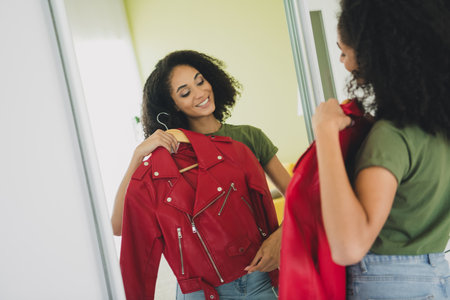 Photo of attractive young woman red jacket hanger dressed green outfit daylight home interior living roomの写真素材