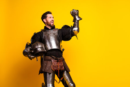 Medieval knight posing in armor against a vibrant yellow background with joyful expressionの写真素材