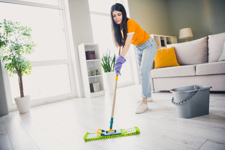 Young woman enjoying a weekend cleaning her stylish living room with a smile in daylight