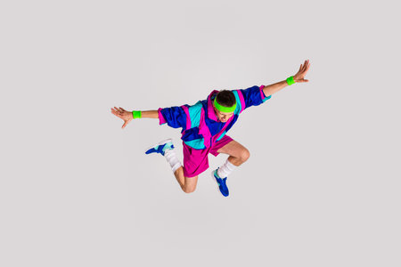 Energetic young man in retro sportswear jumping against light gray backgroundの写真素材