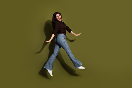 Young stylish brunette woman jumping against a khaki background