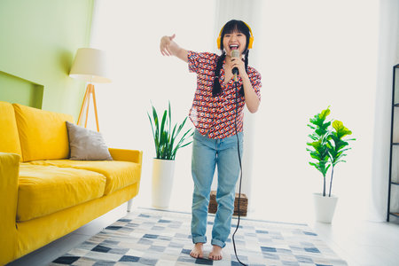Full body portrait of nice young girl sing microphone free time modern interior flat indoorsの写真素材