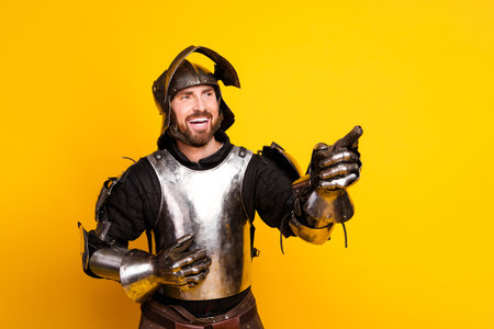 Young man dressed as a medieval knight smiling in armor against a bright yellow backgroundの写真素材