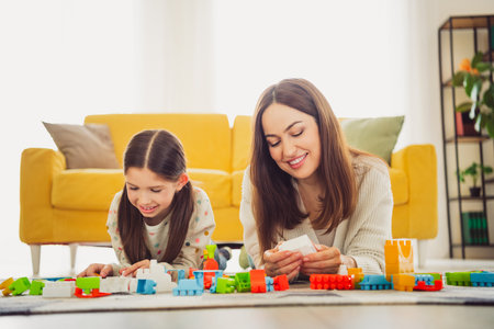 Mother and daughter bonding over a fun building activity in the living roomの写真素材