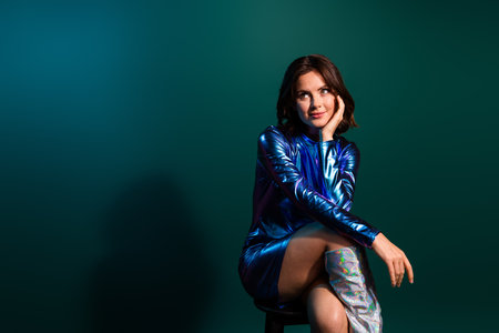 Photo of gorgeous young girl look empty space wear shiny dress neon light dark blue backgroundの写真素材