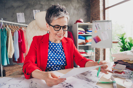 Photo of aged clothing designer lady hold look concept paper loft interior office studio indoors
