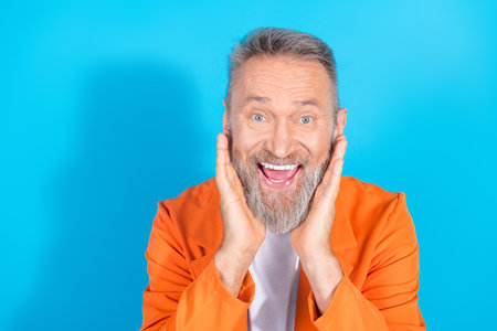 Portrait of modern stylish aged man open mouth empty space wear orange costume isolated on blue...