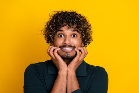 Young man with expressive face showing surprise against bright yellow backdropの写真素材