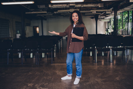 Portrait of young woman clipboard show welcome you business school training conference room indoorsの写真素材