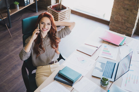 Top view photo of attractive good mood lady ceo dressed formal shirt smiling listening modern gadget indoors workplace workstation loftの写真素材
