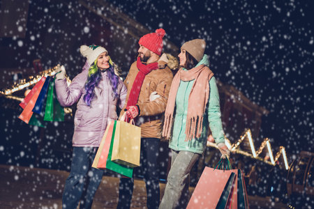 Photo of three cheerful friendly fellows hold packages walk speak communicate x-mas advent outsideの写真素材