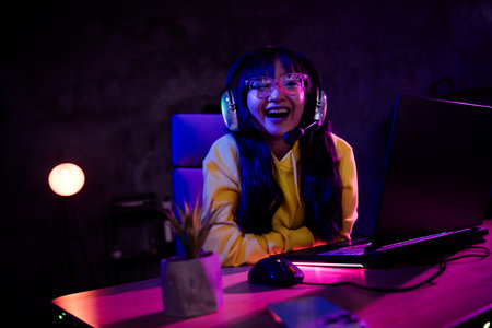 Photo of cute lovely girl good mood laughing play gamer laptop computer game late night indoors house lateの写真素材