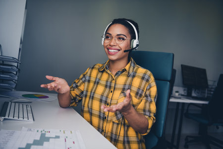 Photo of lovely young lady cheerful call center service dressed yellow plaid shirt comfortable startup office loft room interiorの写真素材
