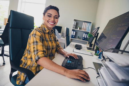 Photo of lovely young lady working computer programmer coding dressed yellow plaid shirt comfortable startup office loft room interiorの写真素材