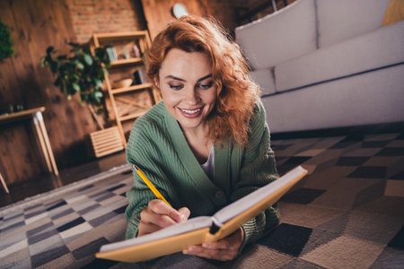 Photo of shiny cute woman dressed green cardigan writing copybook indoors house apartment room