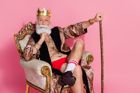 Photo of an eccentric man king lord wear luxurious trendy bathrobe sit throne for casino winners isolated on pink color backgroundの写真素材