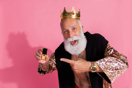 Photo of astonished extravagant ancient leader point finger gold phone wear crown leopard robe isolated on pink color backgroundの写真素材