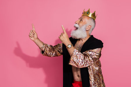 Photo of wealthy monarch crown leopard robe point fingers up empty space isolated on pink color backgroundの写真素材