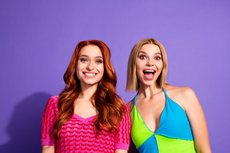 Photo of two pretty gorgeous girls toothy smile open mouth isolated on violet color backgroundの写真素材