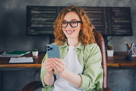 Portrait of young girl computer it specialist use smart phone wear shirt workplace office indoorsの写真素材