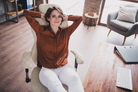 Photo of pretty young girl relax sleepy sit armchair wear brown silk shirt coworking successful nice...