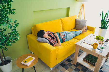 Full size photo of pretty young woman sleep couch hold book weekend modern interior apartment...