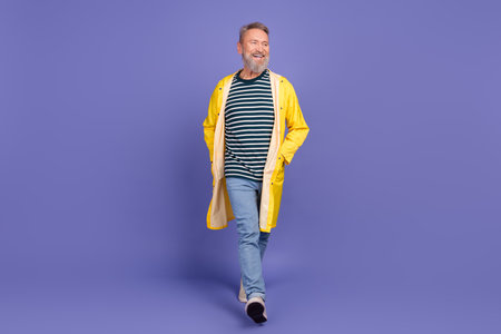 Smiling mature man wearing trendy outfit on a vibrant purple background, radiating happiness and...