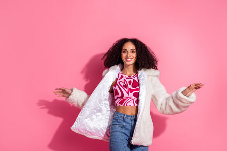 Happy young woman posing stylishly in front of a vibrant pink backdrop, wearing trendy modern clothes and expressing cheerful energy.の写真素材