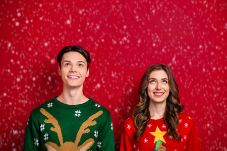 Photo of positive couple wife husband interested look empty blank space banner poster ad isolated on red color backgroundの写真素材