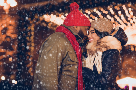 Profile side view portrait of attractive affectionate cheerful couple wife husband visiting festal fair eve cuddling city urban outdoorsの写真素材