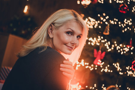 Photo of lovely pensioner lady turn around look camera dreamy dressed christmas outfit day light home party decoration interior roomの写真素材