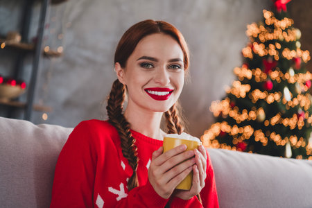Photo of pretty young girl sot couch hold cacao wear sweater christmas festive holiday time apartment indoorsの写真素材