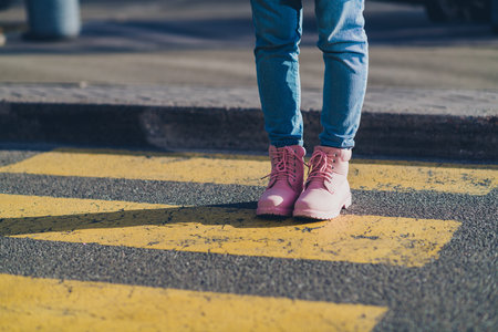 Cropped portrait of young girl pink boots walk pedestrian crossing street outdoorsの写真素材
