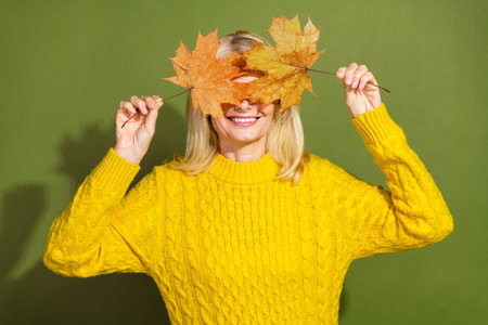 Photo of adorable charming lady wear stylish yellow clothes hold dry maple leaves isolated on green...
