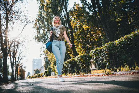 Full size photo of positive young blonde girl walking wear khaki outfit tied shoulders sweater park sunny spring weather outsideの写真素材