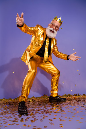 Vertical full body photo of bearded gentleman confetti performance wear fashionable golden clothes isolated on violet color backgroundの写真素材