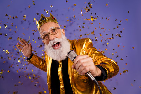 Photo portrait of old macho man confetti sing karaoke dressed glamour stylish golden outfit party isolated on purple color backgroundの写真素材