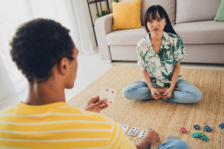 Photo of lovely cute charming family wife and husband sit floor play poker cards indoors apartment flatの写真素材