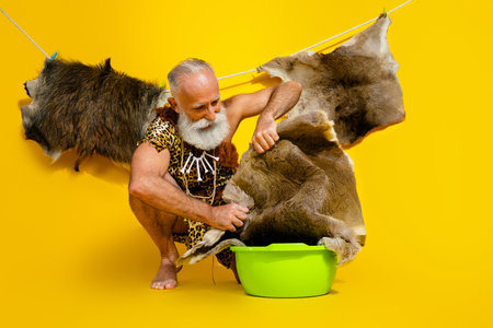 Full length photo of funny cave human wear leopard skin washing basin empty space isolated yellow color backgroundの写真素材