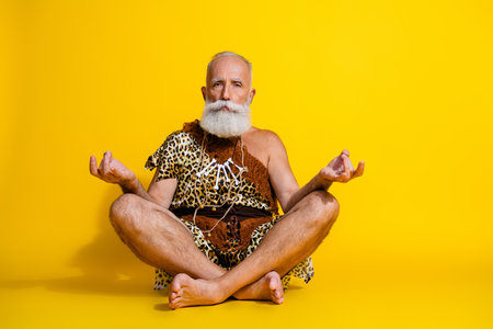 Full size photo of ancient aged man meditate empty space leopard skin clothes isolated on yellow color backgroundの写真素材