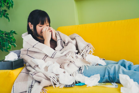 Photo of unhappy sad girl dressed t-shirt covering banket blowing nose indoors house apartment room